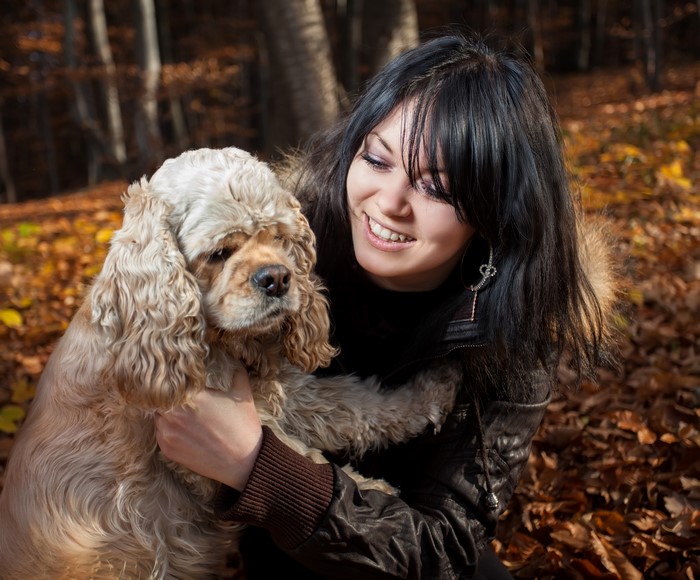 Brunette girl with cocker spaniel in autumn forest