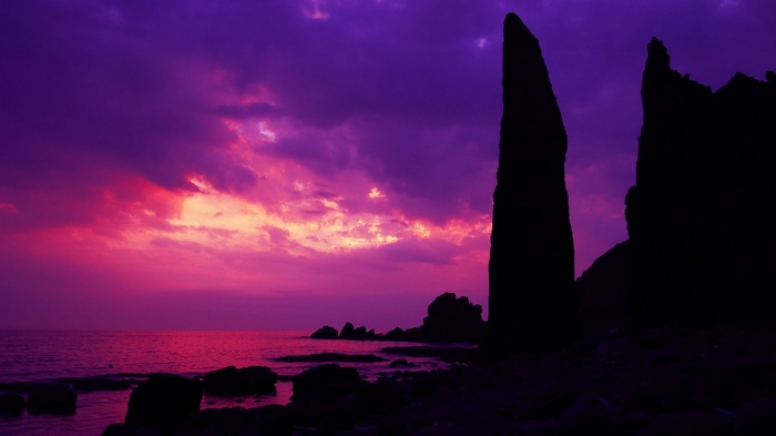 Silhouette of rock formations against a vibrant sunset sky