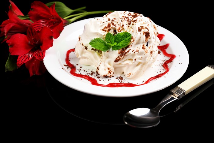 Dessert with whipped cream, mint, and red flowers