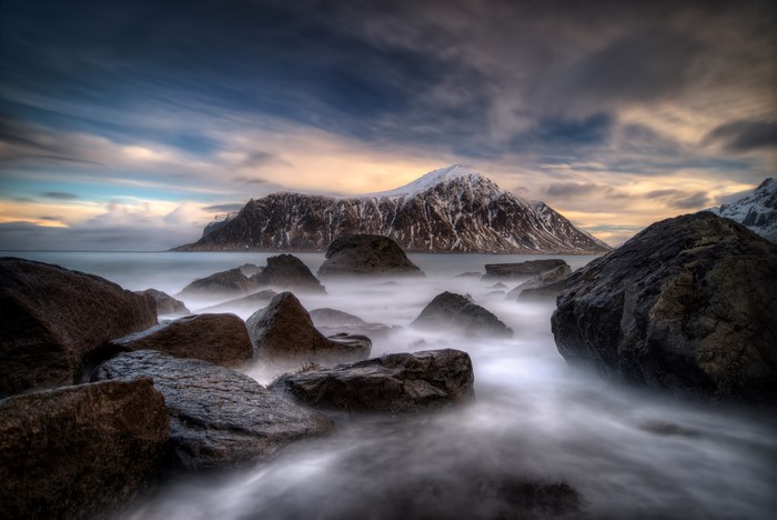 Rocky coast with snow-capped mountain in Lofoten, Norway