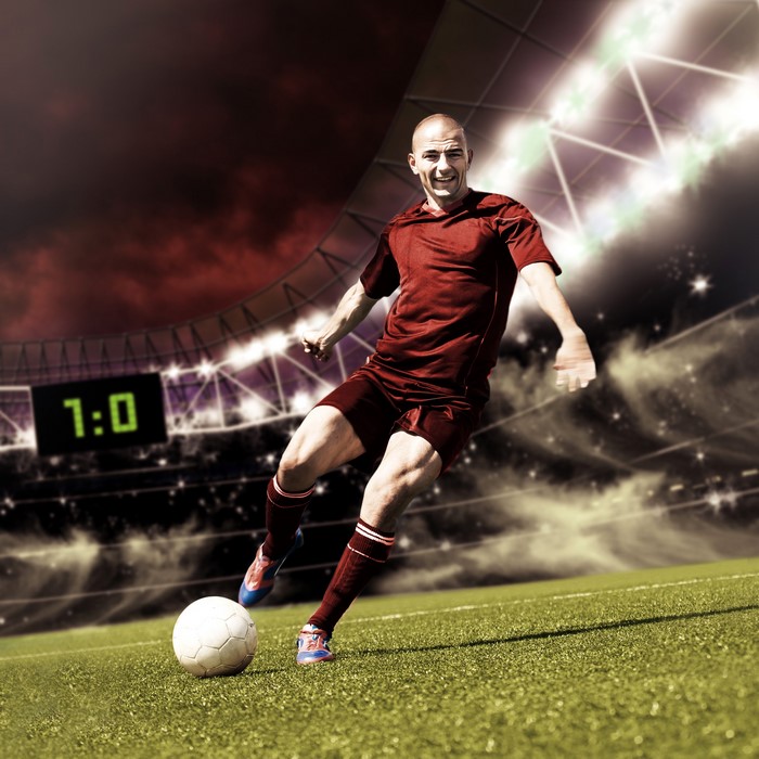 Soccer player kicking ball in stadium