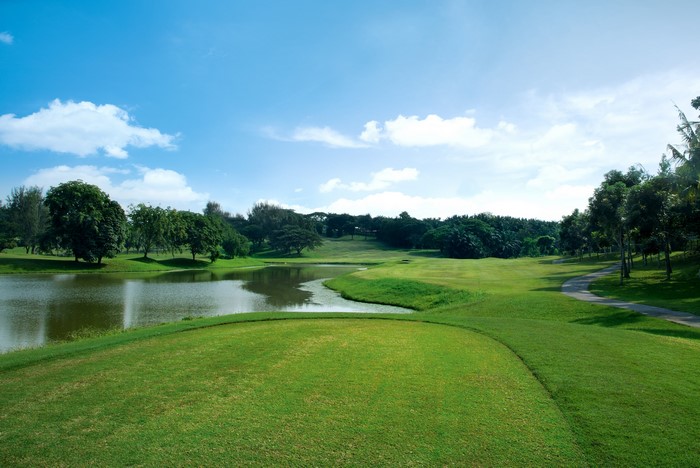 Golf course with a lake and trees under a blue sky