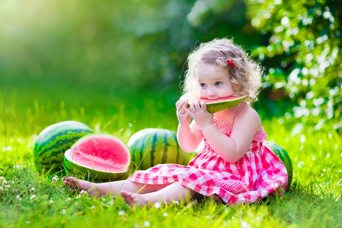 Little girl eating watermelon in grass