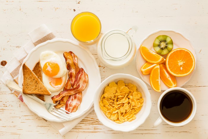 Breakfast with eggs, bacon, toast, cereal, fruit, and coffee