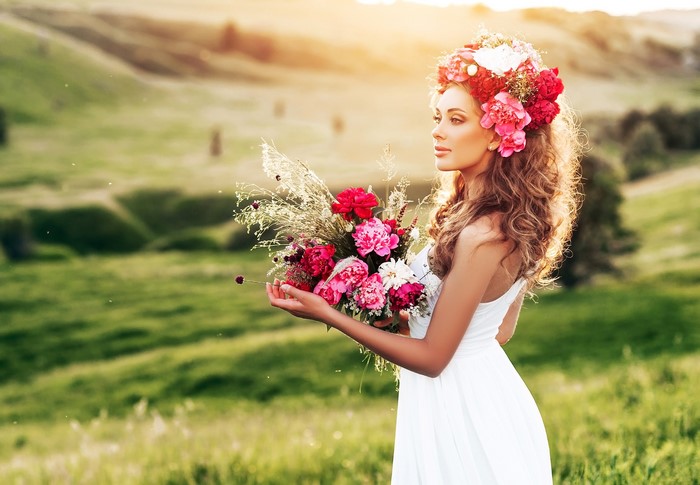 Woman with flower crown and bouquet in a field