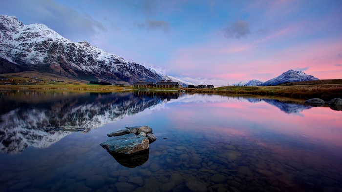 Snow-capped mountains reflected in a calm lake at sunset