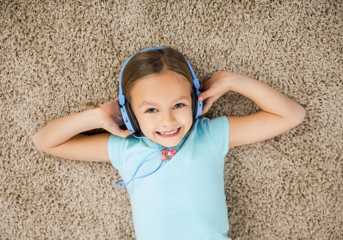 Girl with headphones lying on carpet