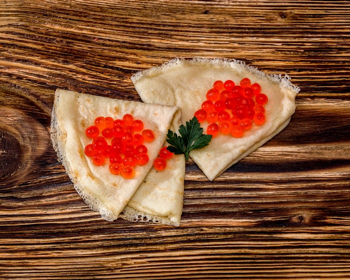 Pancakes with red caviar and parsley