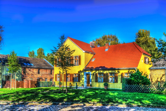 Yellow and brick houses with red roofs under a blue sky