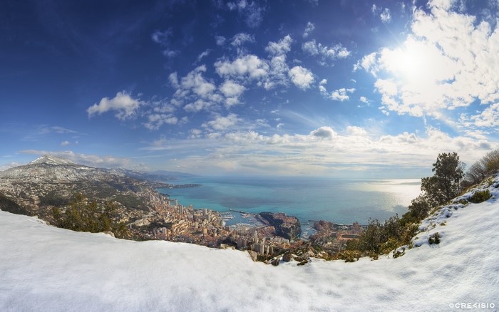 Monaco cityscape with snow-capped mountains and sea