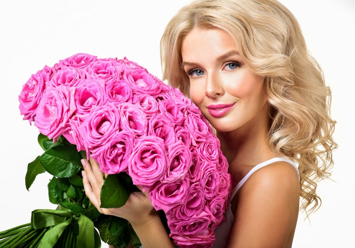 Blonde woman holding a large bouquet of pink roses