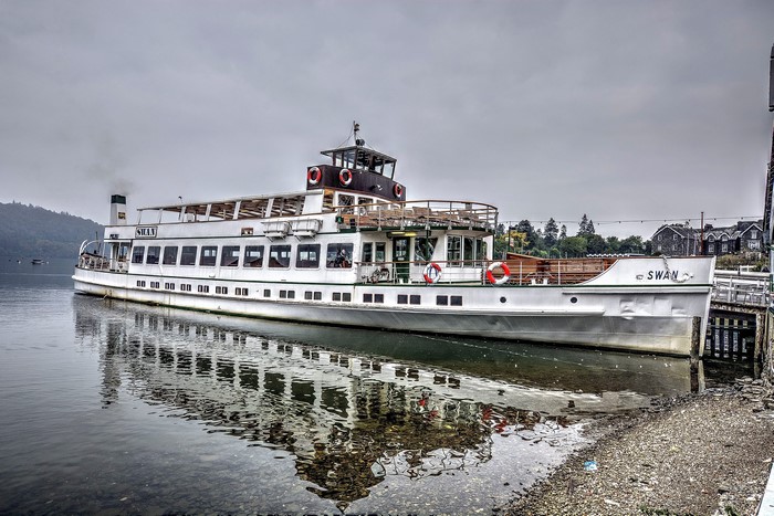 The Swan riverboat docked at a pier on a cloudy day
