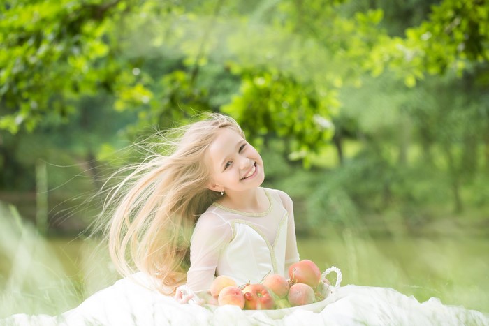 Blonde girl smiling with apples