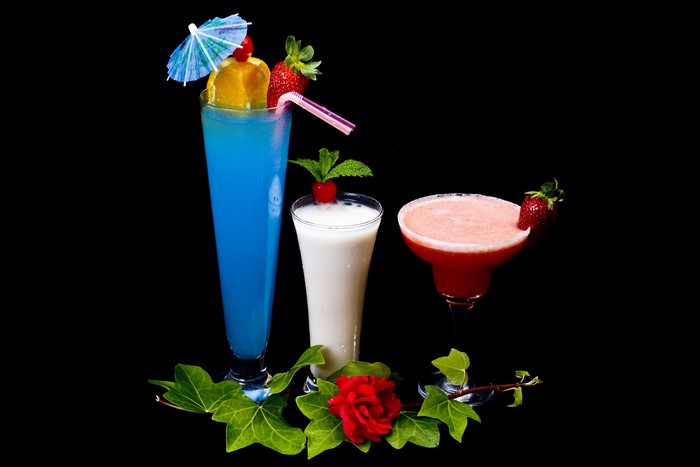 Three cocktails with garnishes on a black background