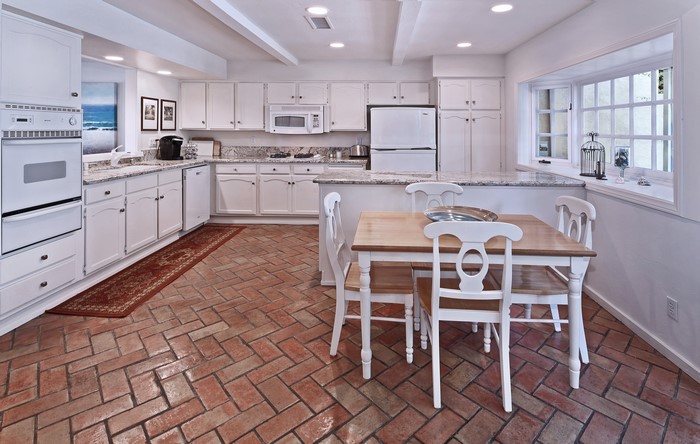 Kitchen with white cabinets, brick floor, and dining table