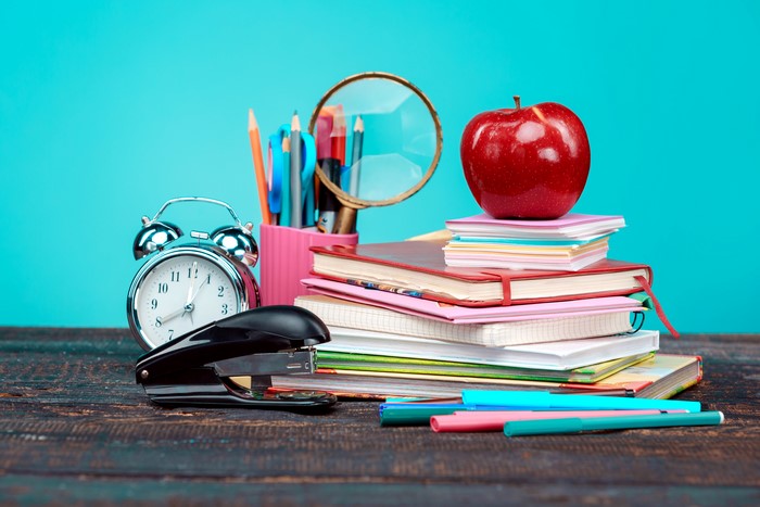 Alarm clock, stapler, books, apple, and school supplies
