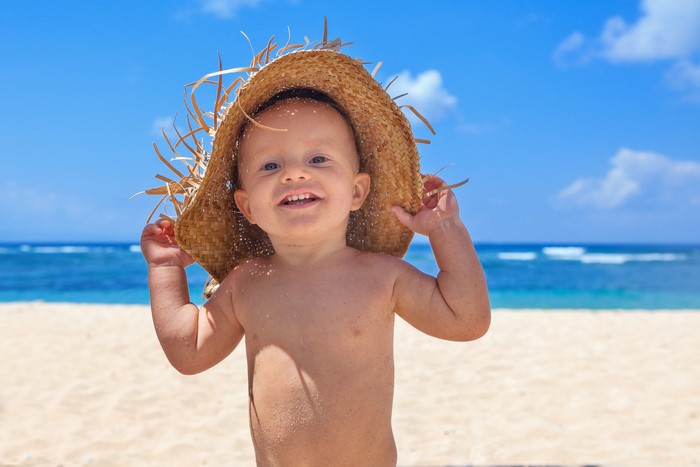 Baby wearing a straw hat on the beach