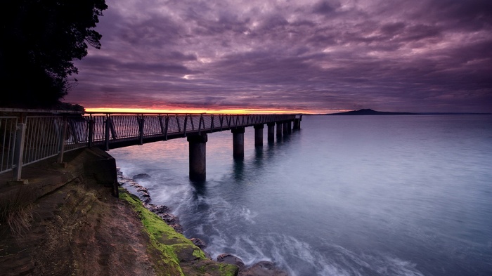 Pier over the ocean at sunset with clouds