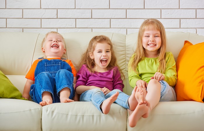 Three Children Laughing on a Sofa