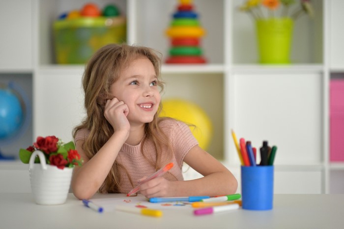 Little girl drawing with colorful pens