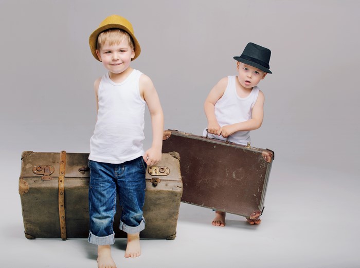 Two boys with suitcases and hats