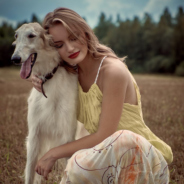 Woman hugging a Borzoi dog in a field