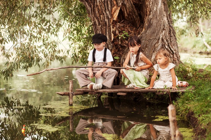 Three children fishing by a tree