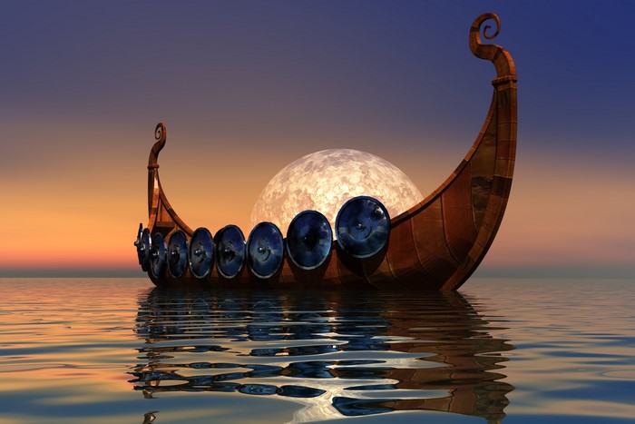 Viking longship with shields on the water at sunset