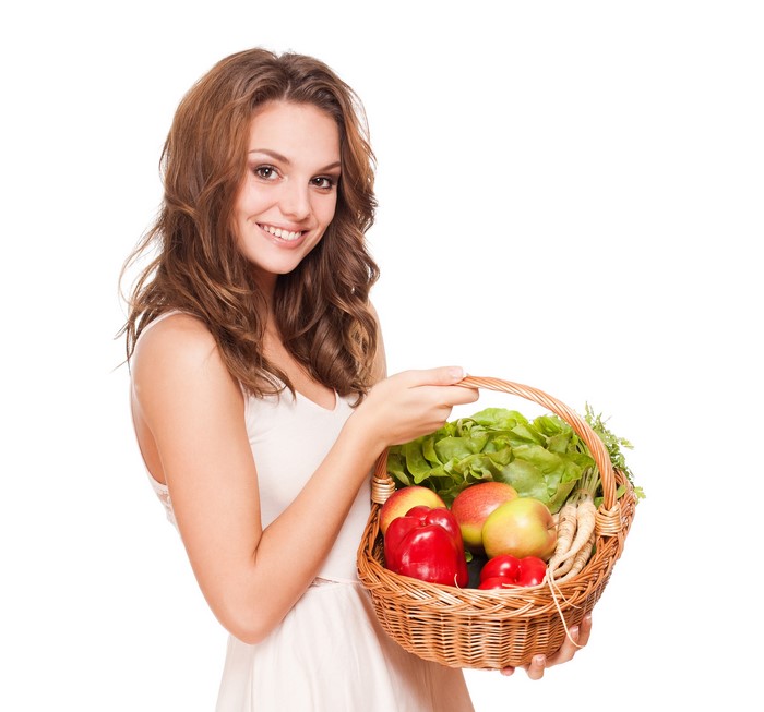Woman holding a basket of fresh vegetables and fruits