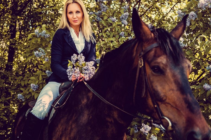 Blonde woman on a horse holding flowers
