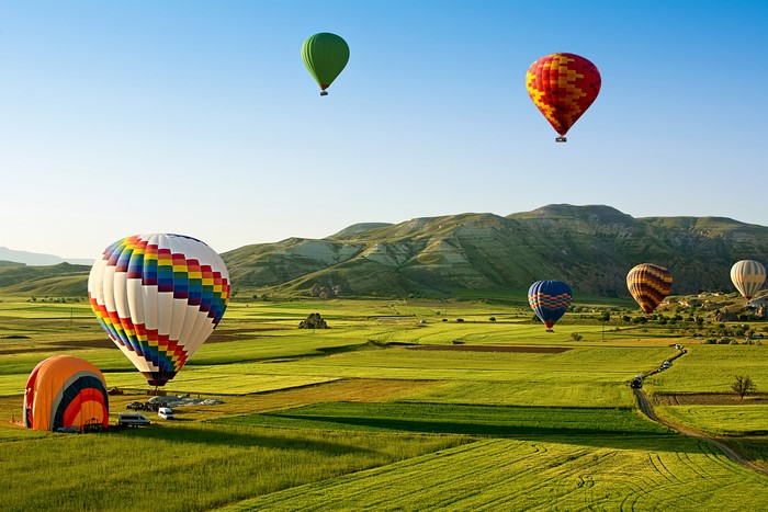 Hot air balloons over green fields in Turkey
