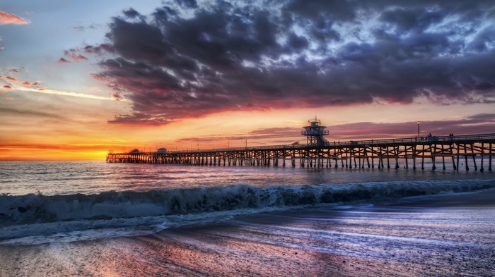 Ocean pier at sunset with dramatic clouds