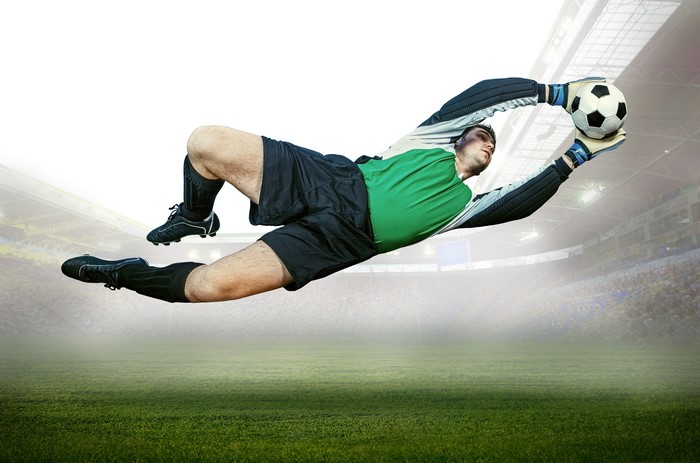 Goalkeeper catching a soccer ball in a stadium