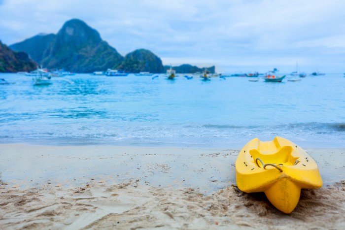 Yellow Kayak on a Tropical Beach with Boats