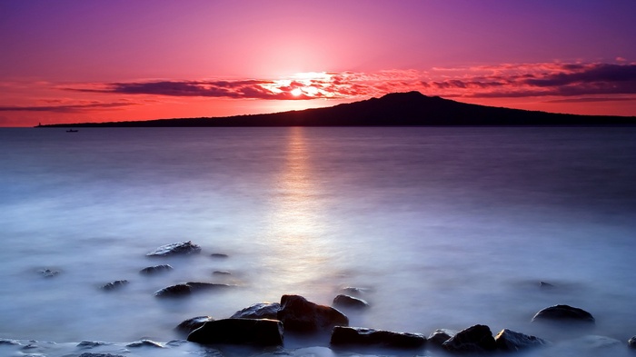 Sunset over a calm sea with a distant island