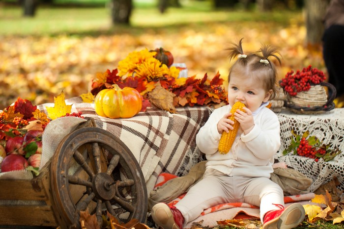 Baby eating corn with autumn decorations