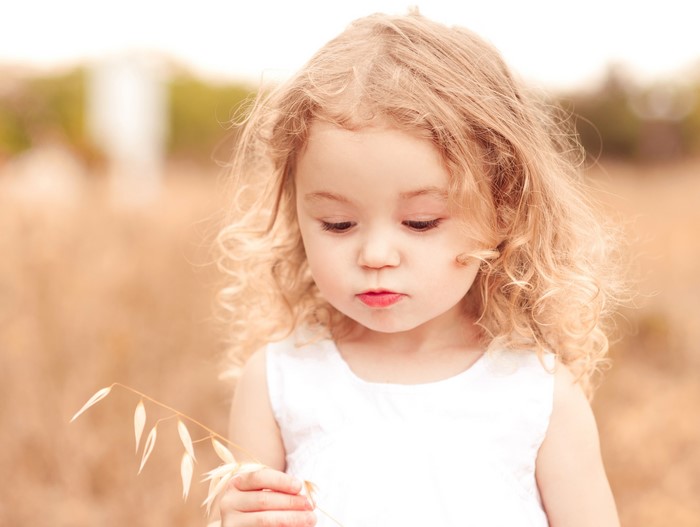 Young blonde girl holding a wheat stalk