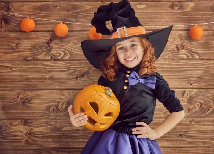 Girl in Witch Costume Holding a Pumpkin