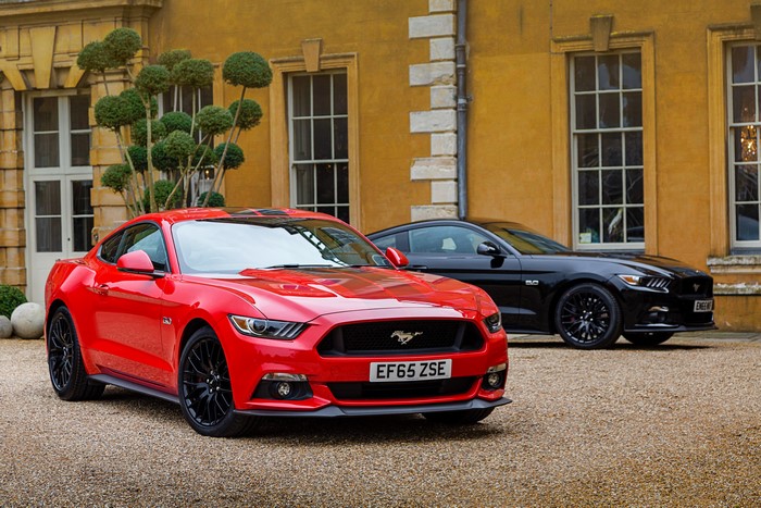 Two Ford Mustang GT Fastback cars parked outside a building