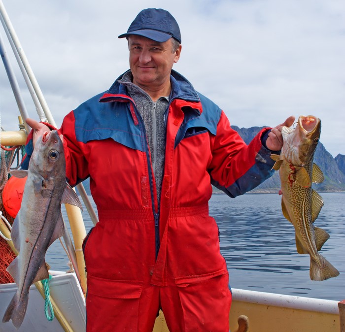Man holding two fish on a boat