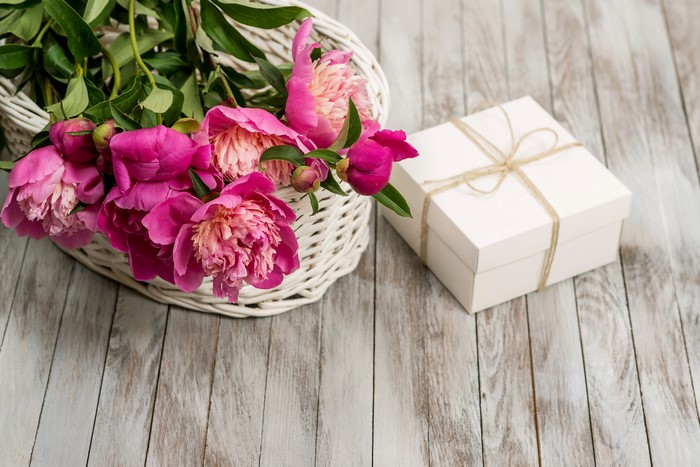 Pink peonies in a basket with a gift box