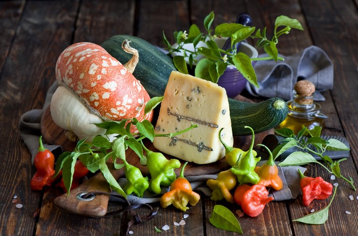 Still life with cheese, pumpkin, zucchini, and peppers
