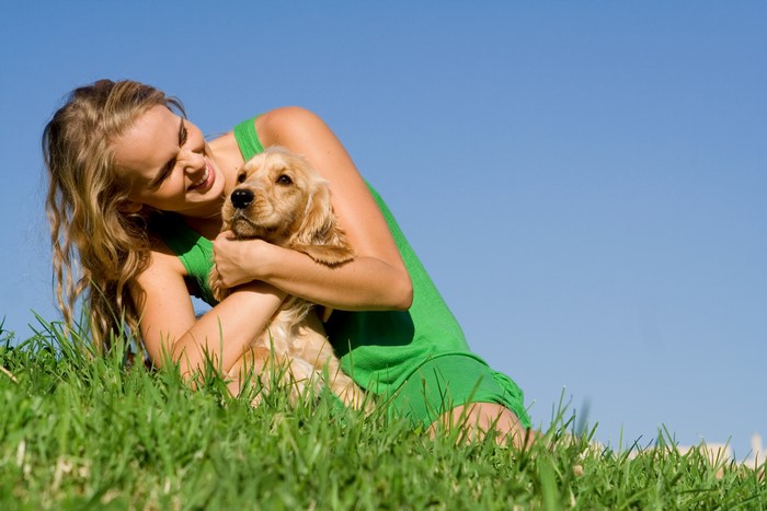 Blonde girl hugging a dog in the grass