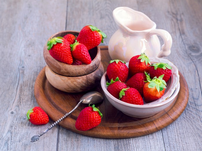 Strawberries in bowls with a jug and spoon