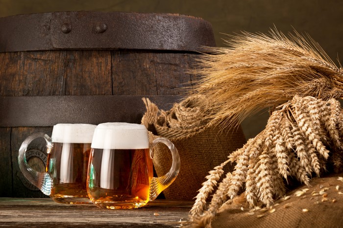 Two Mugs of Beer by a Barrel and Wheat