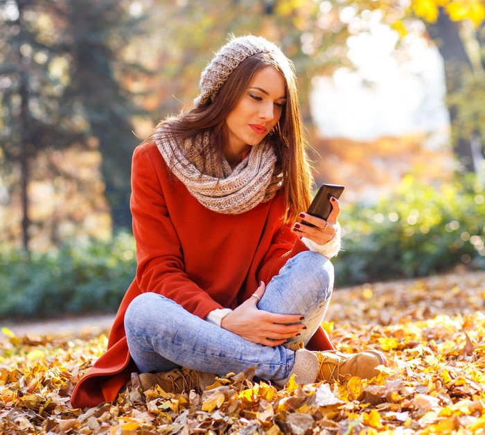 Woman in autumn park using smartphone