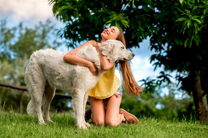 Girl hugging a large white dog outdoors