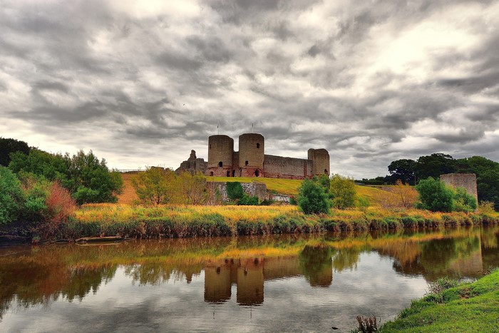 Rhuddlan Castle on a cloudy day reflected in a river