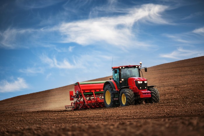 Red tractor plowing a field under a blue sky