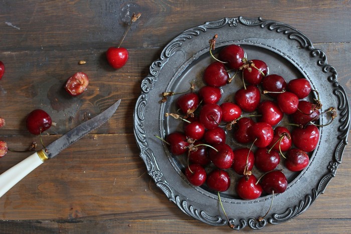 Cherries on a metal plate with a knife
